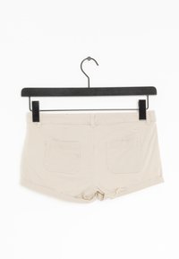 Shorts di cotone beige con una vestibilità slim, dotati di due tasche posteriori e orlo piegato, appesi a un gancio di plastica nero.