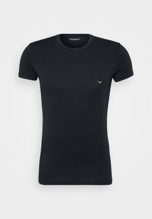 T-shirt noir à manches courtes en tissu lisse, avec un petit logo vert sur la poitrine et un col rond.