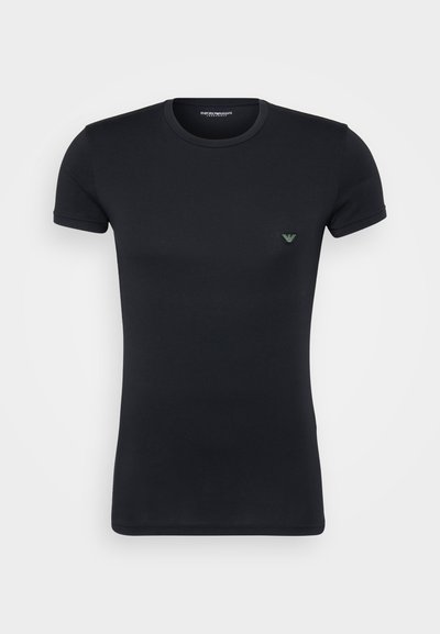 T-shirt nera a maniche corte realizzata in tessuto liscio, con un piccolo logo verde sul petto e collo rotondo.