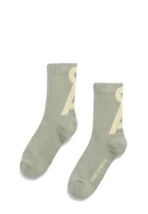 Light green cotton blend socks with ribbed texture, featuring a prominent yellow logo on each side and a reinforced toe.