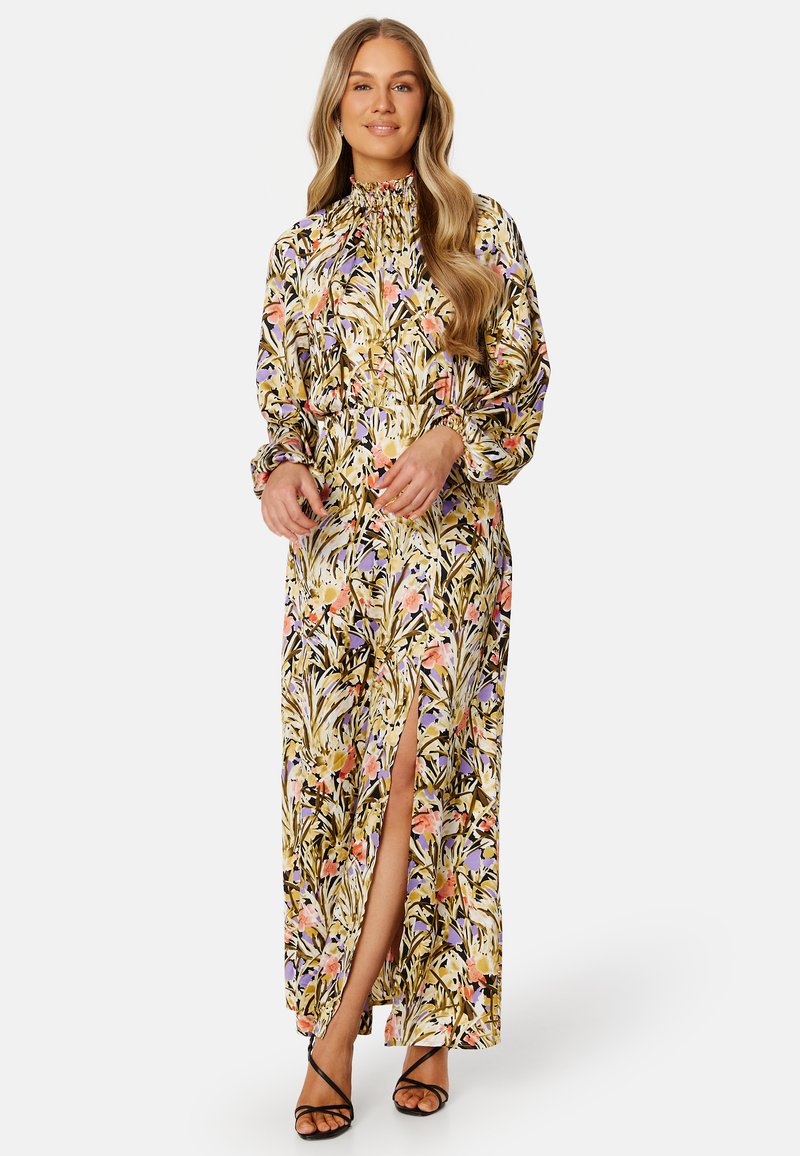 Robe maxi à imprimé floral avec des couleurs vives, un col haut, des manches longues et une fente à l'avant. Fabriquée en tissu léger.