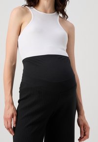 Vit ribbad linne med svart midjeband, matchat med svarta byxor med slimmad rand, med en slät textur och figurnära design.