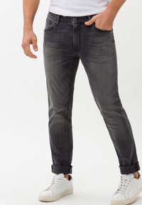 Men's dark gray jeans with a slim fit, featuring five pockets and rolled cuffs. Paired with white low-top sneakers.