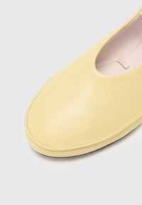 Żółte skórzane buty z okrągłym noskiem, gładką fakturą i minimalistycznym wzornictwem. Posiadają niski dekolt i subtelne przeszycia.