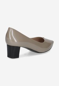 Botte en cuir verni beige avec un bout rond, un talon bas et une texture lisse. Le design présente une silhouette élégante et un éclat subtil.