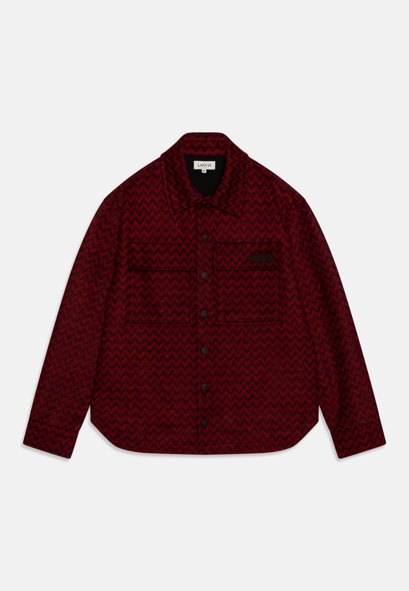 Röd och svart jacka med zigzag-mönster, featuring en spetsig krage, två framfickor och knappstängning. Tillverkad av texturerad tyg.