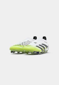 Pair of white and neon yellow Adidas Predator soccer cleats with black stripes and studded soles on a white background.