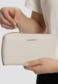 Cartera de piel blanca con cremallera y superficie texturizada, herrajes en tono dorado, y el nombre de la marca "LAZAROTTI" grabado en la parte frontal.