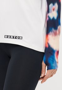 Biała bluzka z długimi rękawami z kolorowymi rękawami w stylu tie-dye, z logo "BURTON" w kolorze czarnym, wykonana z materiału odprowadzającego wilgoć.