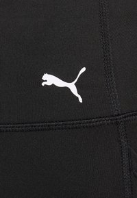 Svarta träningsleggings med en jämn textur och en kontrasterande vit Puma-logotyp. Har platta sömmar för ökad komfort och hållbarhet.