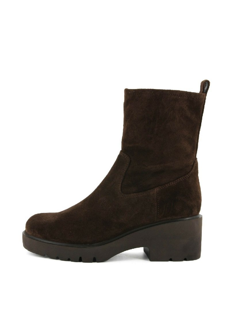 Stivaletto in suede marrone con tacco spesso, punta arrotondata e pannelli elasticizzati laterali. Presenta un anello sul retro per facilitare la calzata.