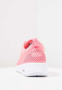 Rosa Nike-sneaker med ett ventilerat meshöverdrag, perforerad häl och vit sula, med en logotyp på baksidan och en tygögla.