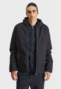 Čierna kapucňová bunda z ľahkej, hladkej tkaniny s predným zipsom, elastickými manžetami a bočnými vreckami pre väčšiu funkčnosť.