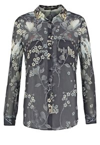 Blouse noire transparente à manches longues avec motif floral, devant boutonné et col orné.