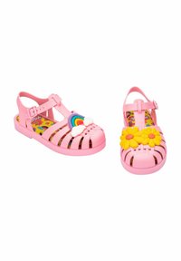 Chanclas de gelatina rosa con diseño calado. Una decorada con un arcoíris y una nube, la otra con flores amarillas. Plantillas impresas coloridas.