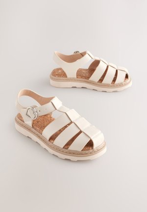 Sandales blanches en cuir avec semelle en liège, plusieurs larges brides, et bride arrière à la cheville avec garniture argentée ; semelle texturée pour une meilleure adhérence.