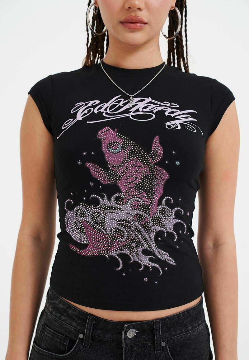 Top corto ajustado negro con un diseño de pez koi en rosa y acentos de rhinestones, con patrones de olas debajo. Mangas cortas y escote redondo.