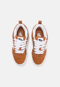 Brune ruskinds sneakers med hvide snørebånd, polstret krave og gummisåler. Har et sort logo mærke på tungen og en hvid side stripe.