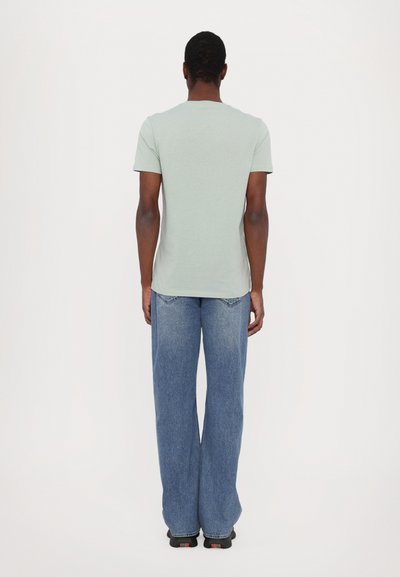 Mintgrønn t-skjorte med korte ermer og rund hals, kombinert med løst sittende blå denimjeans. Teksturert stoff, klassisk design.
