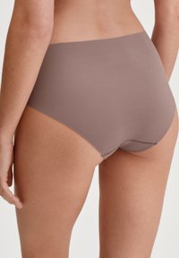Culotte taille haute, sans coutures, dans une couleur marron doux et atténué. Tissu lisse avec une finition mate et un design minimaliste.