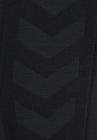 Sort stof med et tekstureret mønster af tre nedadvendte chevroner i en en smule mørkere nuance.