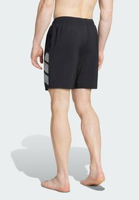 Bañador negro con cinturilla elástica, que presenta un patrón geométrico gris en el lateral, fabricado en un material ligero y de secado rápido.