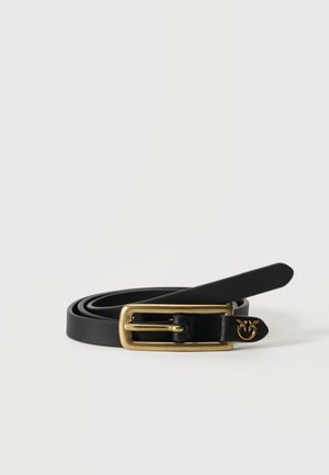 Cintura nera in pelle arrotolata con fibbia rettangolare in ottone e un piccolo emblema dorato vicino alla punta su sfondo bianco.