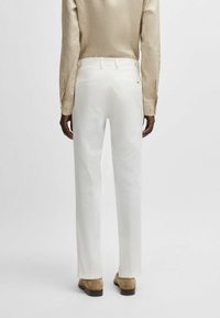 White tailored trousers made of soft fabric, featuring a zip and button closure, with two back pockets and a straight leg design.
