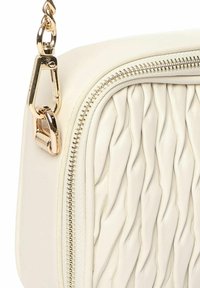 Witte leren crossbody tas met een geborduurd textuur, gouden hardware en een ritssluiting. Verstelbare ketting schouderband voegt functionaliteit toe.
