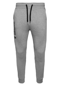 Graue Sweatpants aus weichem Material, mit schwarzen Kordeln, schmal zulaufenden Beinen und einem Logo, das vertikal an der linken Seite aufgedruckt ist.
