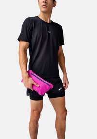 Black moisture-wicking short-sleeve shirt and black shorts, holding a bright pink zippered pouch with a contrasting blue zipper.