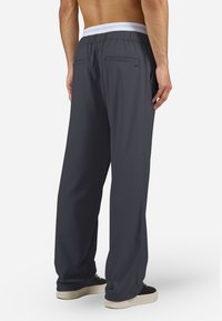 Sötétszürke sportnadrág rugalmas derékpánttal, két hátsó zsebbel, valamint könnyű, sima tapintású anyagból.