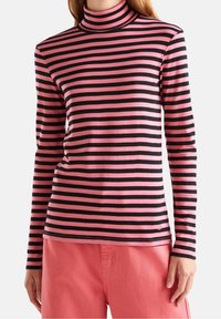 Långärmad polotröja med växlande rosa och svarta horisontella ränder, tillverkad av mjukt tyg med en figurnära design.