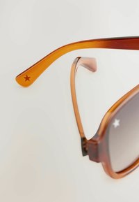 Pruun tortoiseshell solaarprillid koos gradient hallide läätsedega. Poolde ääres on täppide detailid, millel on tähtkäsitlus temple lõpus.