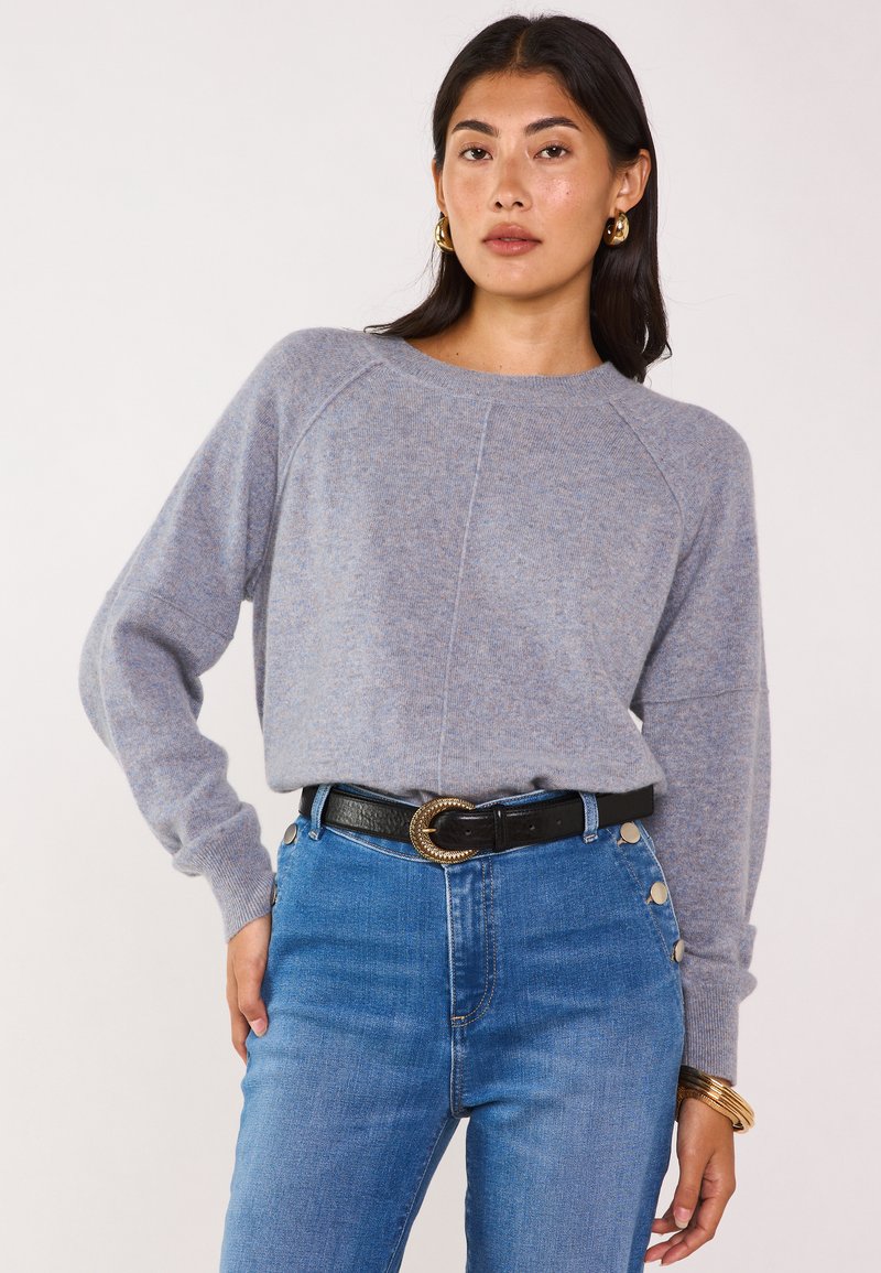 Maglione grigio lavorato a maglia con una vestibilità comoda, collo rotondo e maniche raglan, abbinato a jeans blu a vita alta e una cintura nera con fibbia dorata.