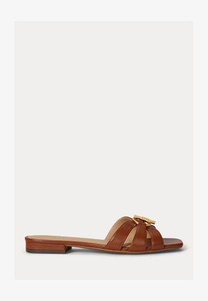 Bruine leren flatte sandaal met drie bandjes en een gouden metalen gesp op een witte achtergrond.