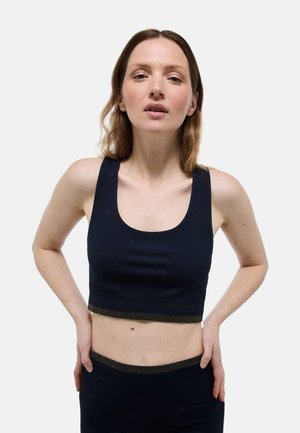 Top court côtelé bleu marine avec bretelles larges et ourlet accentué par de l'or. Associé à un bas assorti, mettant en avant un design ajusté et un tissu texturé.