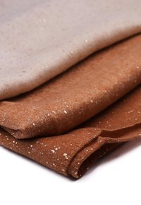 Tre tessuti piegati in diverse tonalità: beige chiaro, marrone e marrone scuro. Ognuno presenta una superficie texturizzata con accenti dorati scintillanti.