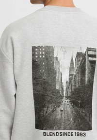 Sweatshirt gris avec un grand graphique noir et blanc d'une ligne d'horizon de ville, avec le texte "BLEND SINCE 1993" en bas.