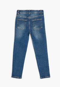 Pantalones vaqueros de mezclilla en un lavado azul medio, con un diseño ajustado, bolsillos traseros estándar y una cintura clásica con pasadores para cinturón.