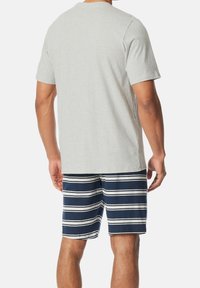 Camiseta de algodón gris de manga corta combinada con bañador a rayas en navy y blanco. La camiseta tiene un escote redondo y un ajuste relajado.