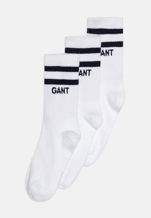 Weiße Baumwollsocken mit marineblauen Streifen, versehen mit dem "GANT"-Logo in marineblauer Schrift. Drei Paare sind ausgestellt, um die gerippte Textur und die Knöchellänge zu zeigen.