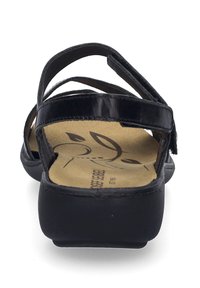 Sorte sandaler med en glat, blank syntetisk overdel, der har korslagte stropper og en polstret sål med bladdetaljer.