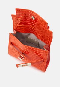 Sac à main orange embossé crocodile avec quincaillerie dorée ; présente une fermeture à pression et une poche intérieure étiquetée. Extérieur texturé.