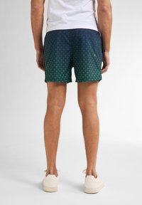 Costumi da bagno da uomo con motivo a scaglie in verde e navy, realizzati in tessuto leggero. Lunghezza corta con vita regolabile con coulisse.