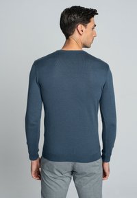 Dopasowany sweter z długim rękawem w ciemnoniebieskim kolorze, o prążkowanej fakturze, z okrągłym dekoltem, o gładkim wykończeniu i subtelnych detalach szwów na ramionach.