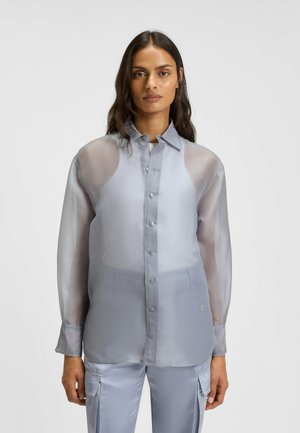 Camicia button-up leggera grigio chiaro, trasparente, con colletto e maniche lunghe, caratterizzata da una texture liscia e da bottoni metallici discreti.