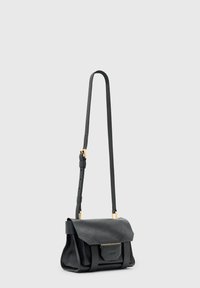 Μαύρο δερμάτινο τσαντάκι ώμου με υφασμάτινη επιφάνεια, κλείσιμο με καπάκι και ρυθμιζόμενο λουρί. Διαθέτει εξαρτήματα σε χρυσό τόνο και μια μικρή μπροστινή τσέπη.