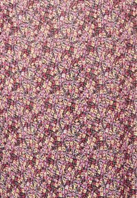 Tecido com um fundo escuro apresentando um padrão floral denso e repetitivo em tons de rosa, amarelo e roxo; superfície texturizada.