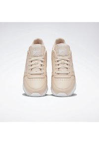 Paire de baskets Reebok beiges avec semelles blanches, vue de face, lacées et placées côte à côte sur un fond uni.